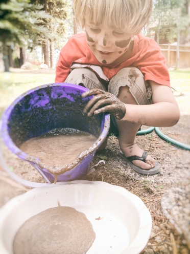 a boy makes a messy play mud pie